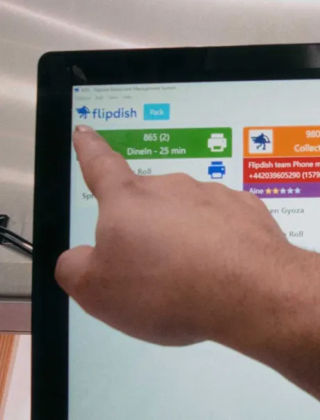 A hand hovering over the Flipdish KDS Screen